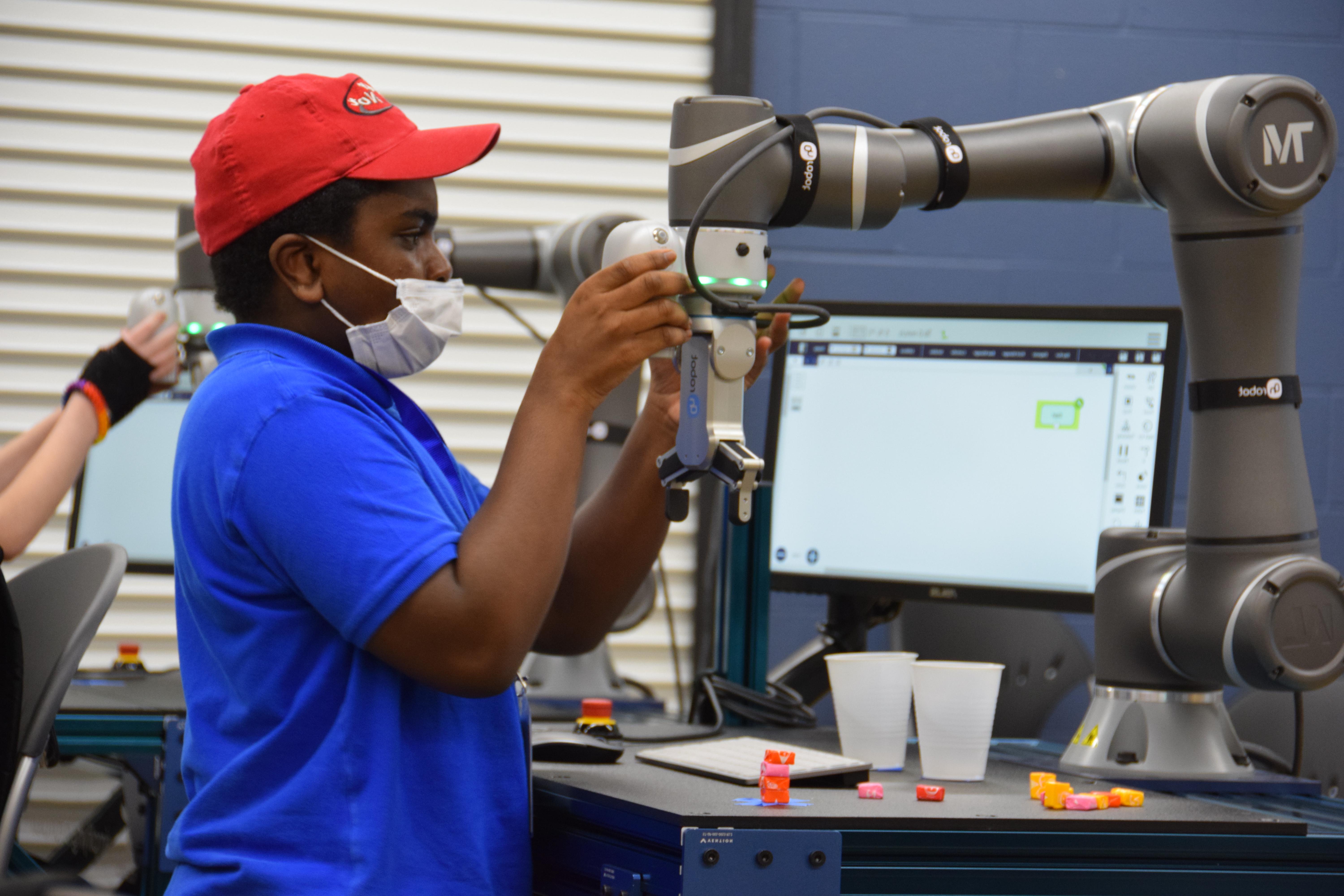 A high school student attending the 澳门足球博彩官方网址 Jasper STEM Academy programs a collaborative robot or cobot in the Cobot Learning Lab in the CTIM on the 澳门足球博彩官方网址 Jasper Campus.